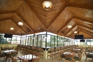 A spacious indoor area with wooden ceiling beams and large windows offering a view of the outside. - Joy Palace (Nairobi)