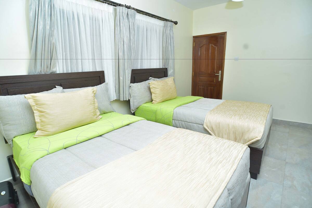 A room with two beds, a wooden door, and a curtain.