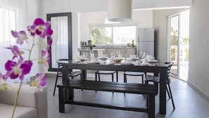 A modern dining area with a dark wooden table set for a meal, a bench, and a hanging light fixture. - Ocean Palms Residences (Cabarete)