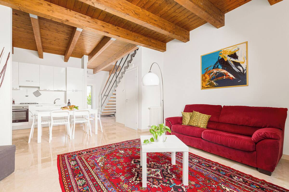 Ein modernes Wohnzimmer mit einem roten Sofa, einem weißen Couchtisch und einem gemusterten Teppich.