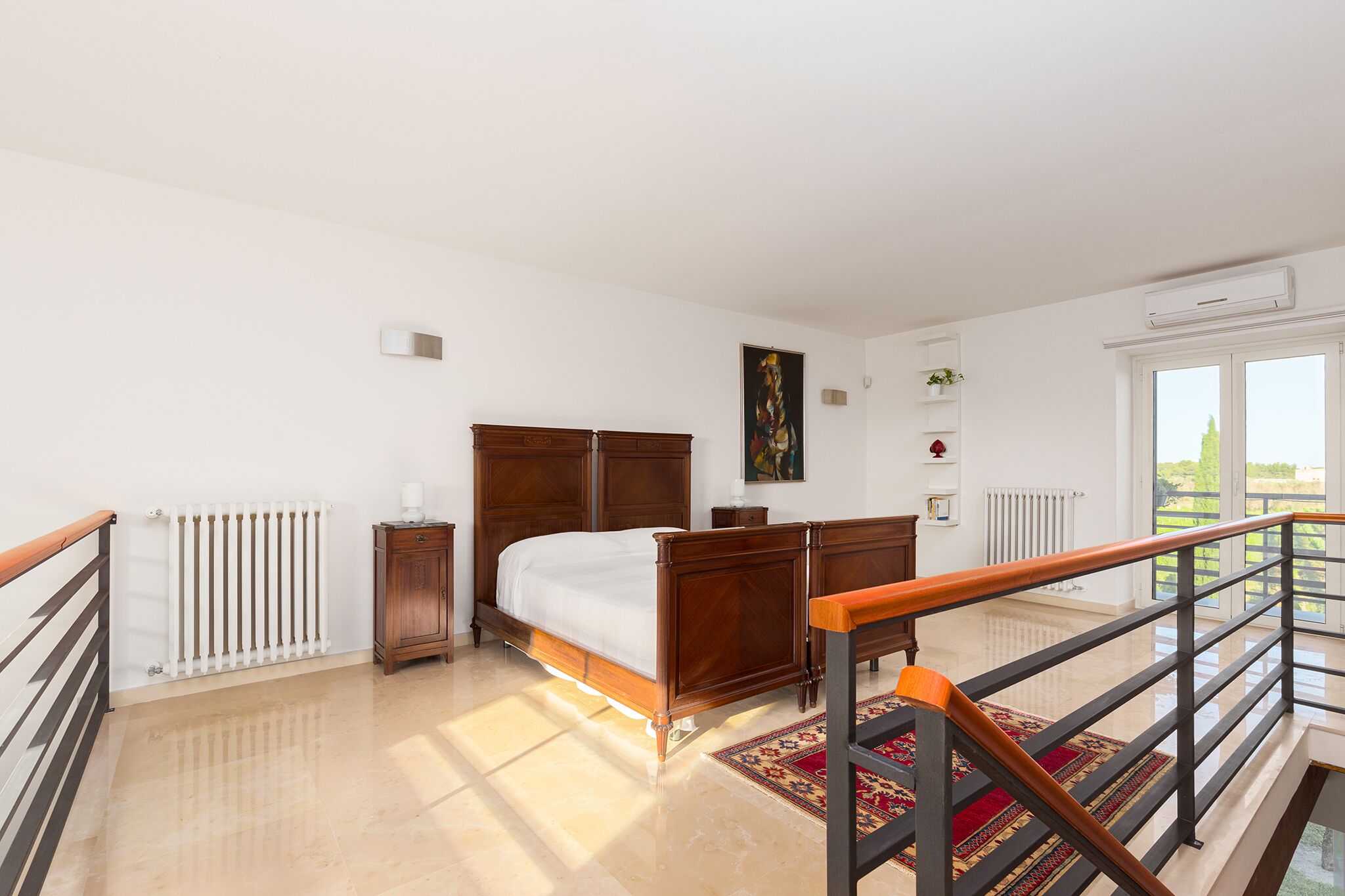 A bedroom with a wooden bed, a radiator, a window, and a view of the outdoors.