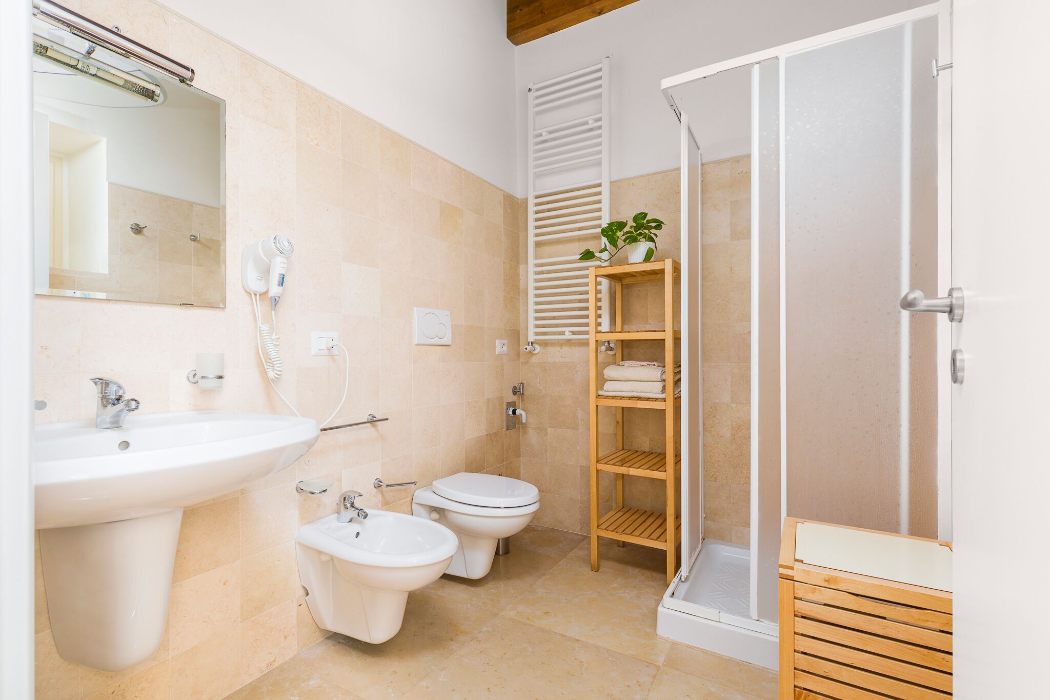 A modern bathroom with a sink, bidet, toilet, and shower.