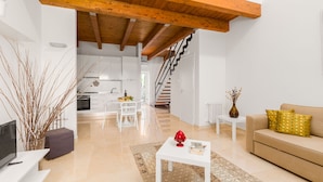 A modern living room with a sofa, a coffee table, and a TV. There is a staircase leading to an upper level. - Tenuta Giardini Nuovi (Novoli)