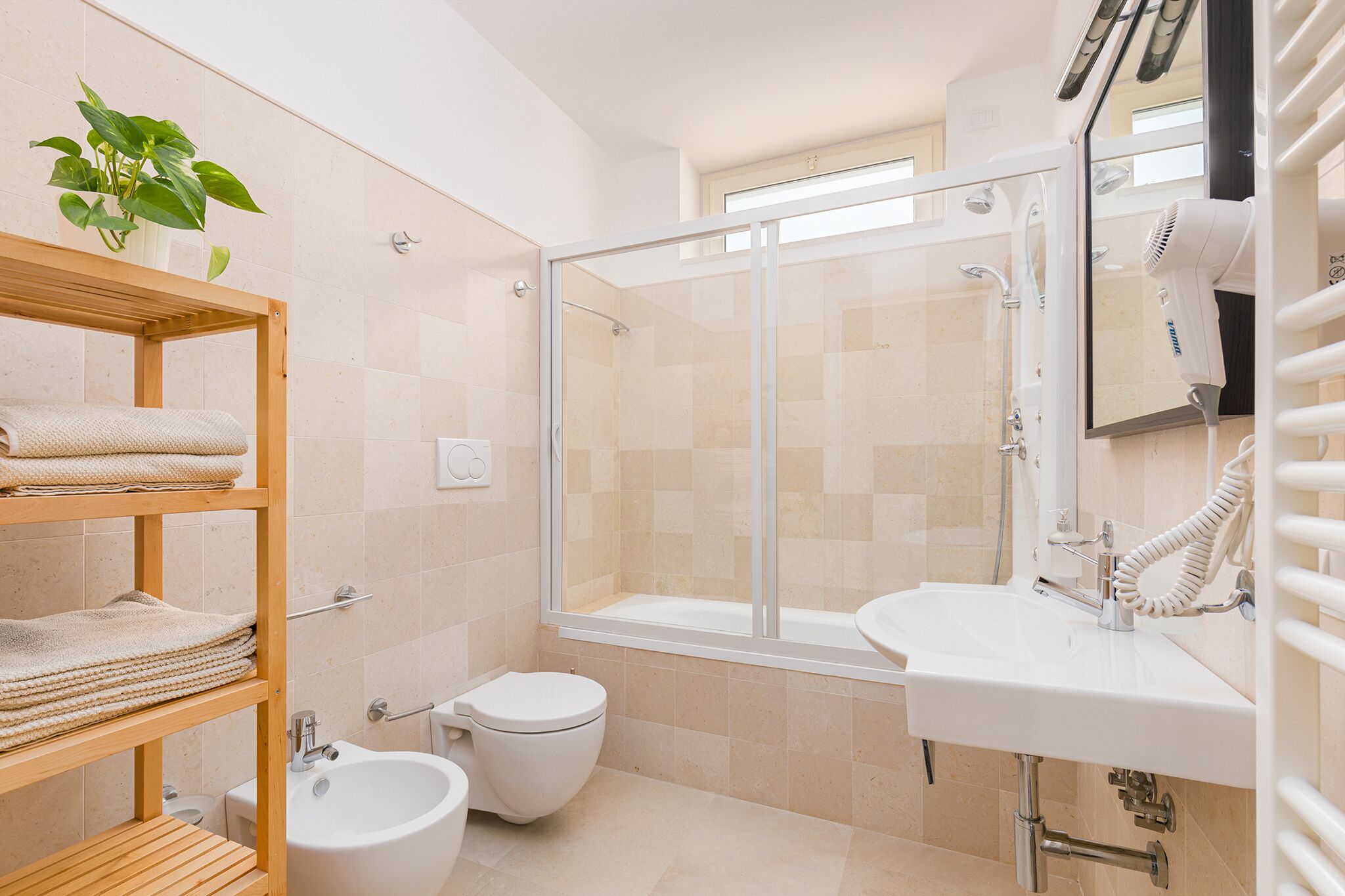 A modern bathroom with a glass-enclosed shower, a white sink, and a bidet.