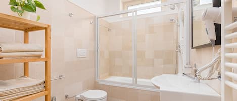 A modern bathroom with a glass-enclosed shower, a white sink, and a bidet.