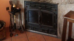 Une cheminée en pierre agrémentée de divers objets décoratifs, comme un chandelier, une petite statue et une cuillère en bois.