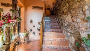 Un escalier orné de carreaux décoratifs menant à l’étage supérieur, entouré de plantes en pot et d’une enseigne en bois sur laquelle on peut lire « BIENVENIDOS ».