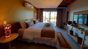 A hotel room with a large bed, a desk with a TV, and a balcony with curtains.