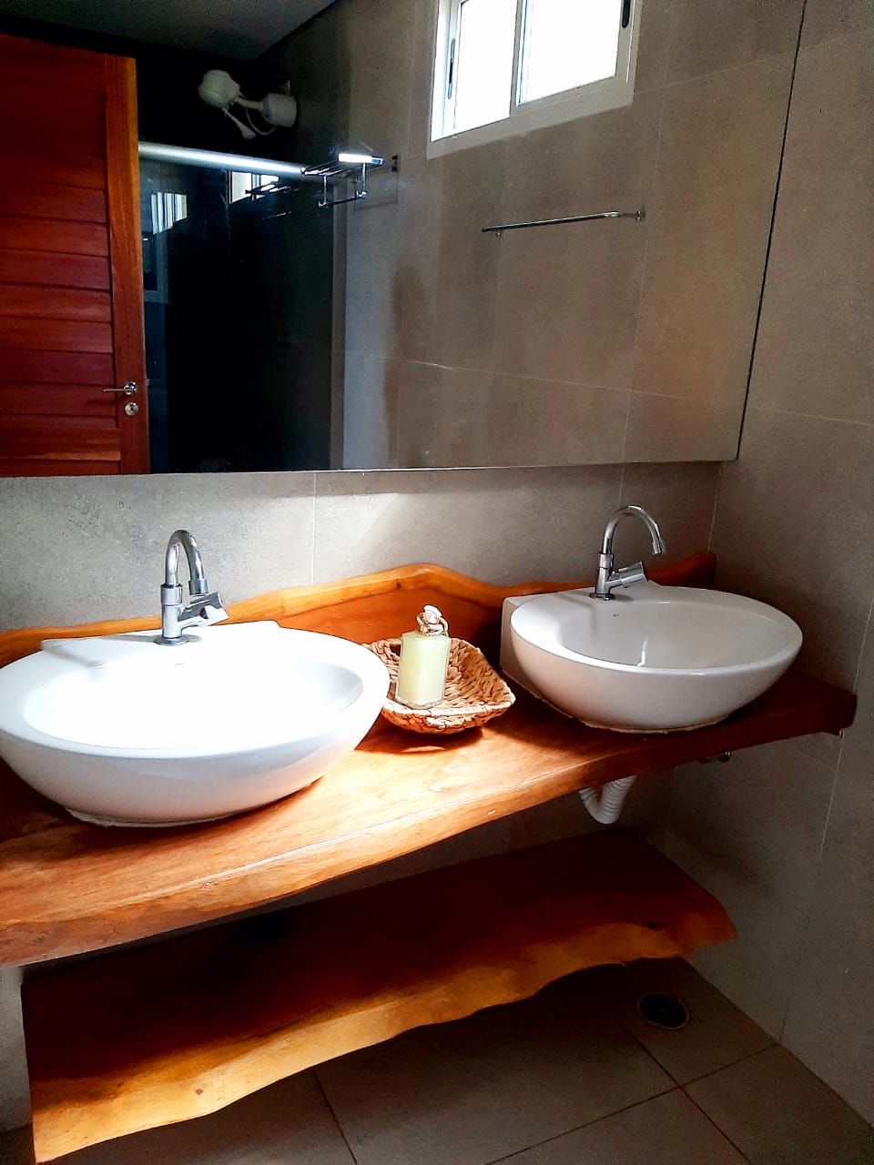 A bathroom with two sinks, a wooden vanity, a mirror, and a towel rack.