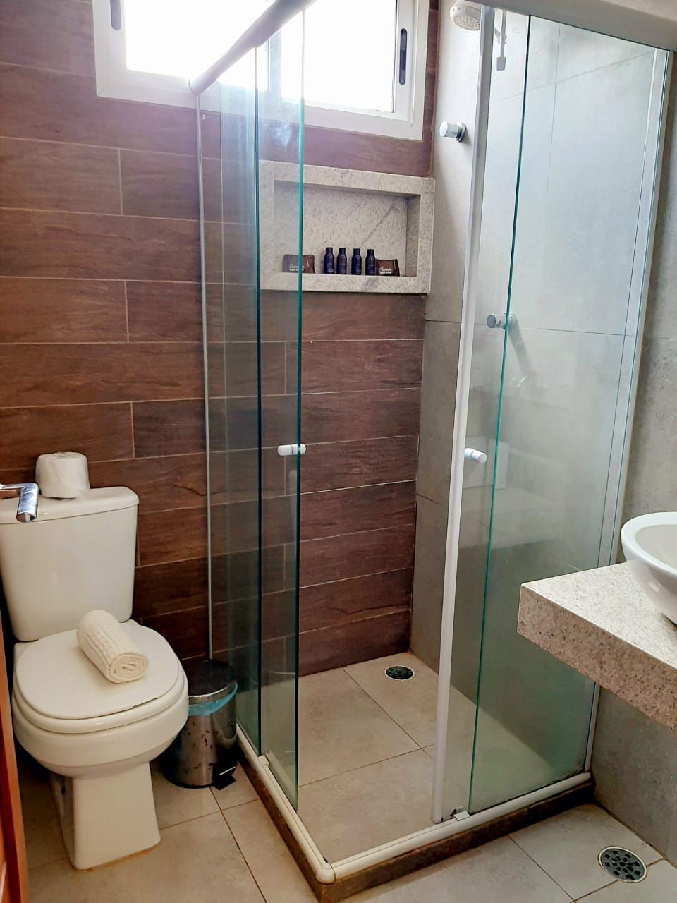 A bathroom with a glass-enclosed shower, a toilet, and a sink.