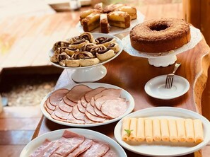 Een buffet met diverse gerechten, waaronder plakjes ham, broodjes en een bundt cake.