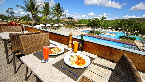 Comedor con vista a la piscina, mobiliario exterior y ambiente tropical.