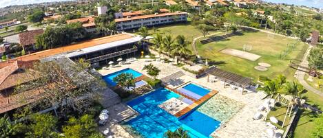 A resort with a large swimming pool, outdoor seating, and a golf course.