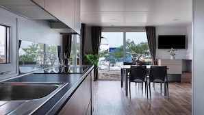 Una cocina moderna con una isla grande, un comedor con sillas y un televisor montado en la pared.