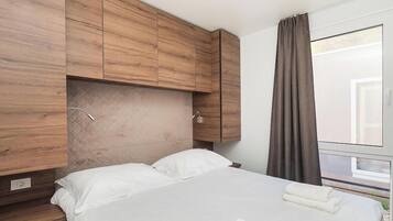 A modern hotel room with a large bed, wooden headboard, and a window with curtains.