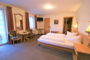 Ein Hotelzimmer mit Bett, Schreibtisch, Stuhl, Fernseher und einer Badezimmertür.
