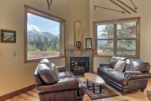 A living room with leather sofas, a fireplace, and large windows offering mountain views. - 120 Rachel Lane Private Home with Hot Tub (Breckenridge)