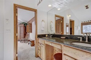A bathroom with wooden cabinetry, a granite countertop, and a large mirror.