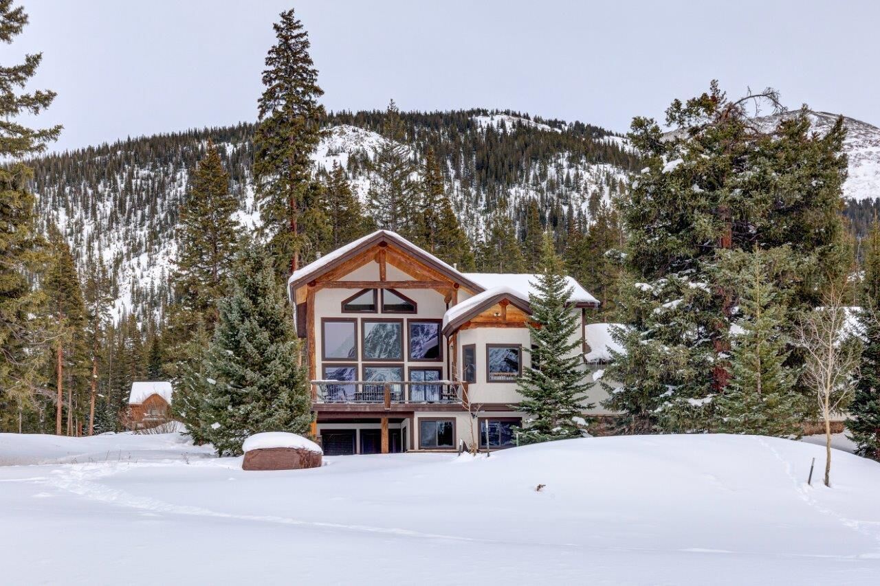 Un chalet à deux étages, avec une façade en bois, de grandes fenêtres et un balcon.