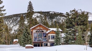 Un chalet à deux étages, avec une façade en bois, de grandes fenêtres et un balcon.