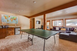 A spacious living area with a ping pong table, a sofa, and a kitchen area with a map on the wall.