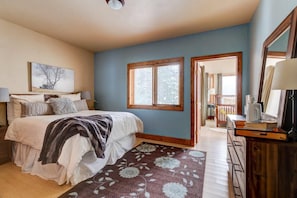 A bedroom with a bed, a window, a dresser, and a painting on the wall.