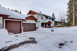 Ein mit Schnee bedecktes Gebäude mit Garage, Holzfassade und einem verschneiten Dach.