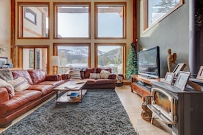 Ein geräumiges Wohnzimmer mit großem Fenster, Kamin und Fernseher.