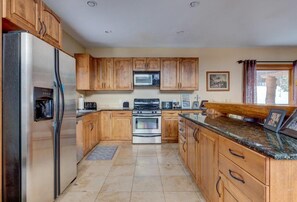 A kitchen with wooden cabinets, stainless steel appliances, and granite countertops.