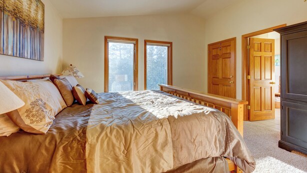 A bedroom with a large bed, two windows, a wooden door, and a dark cabinet. - 72 Clubhouse Rd Private Home with Hot Tub (Breckenridge)