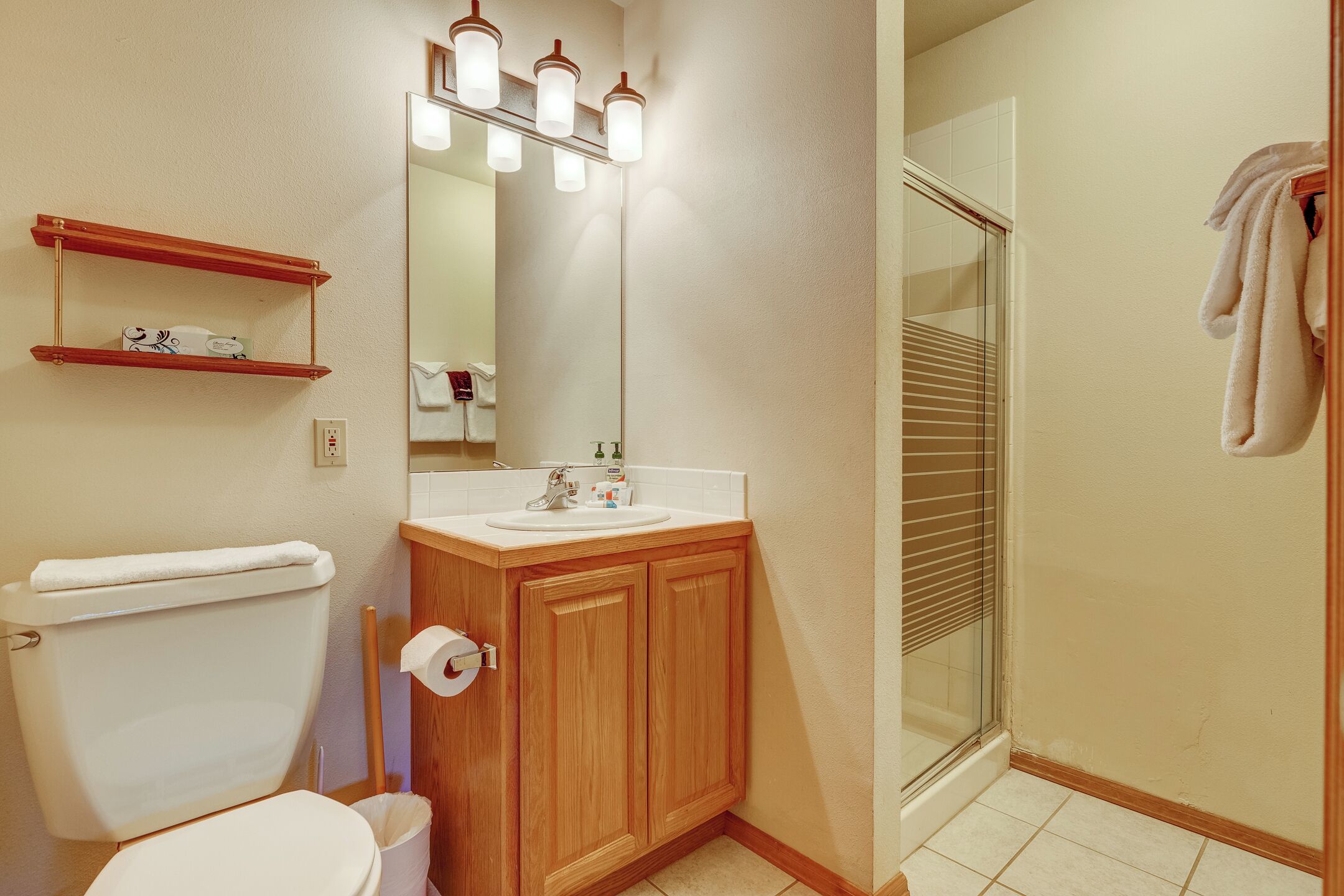 Une salle de bain comprenant des toilettes, un lavabo, un miroir et une douche.