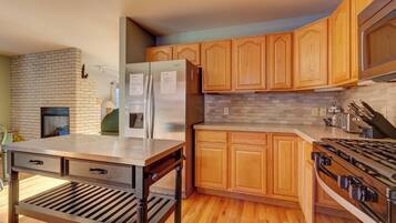 A modern kitchen with wooden cabinets, a stainless steel refrigerator, a built-in oven, and a gas stove.
