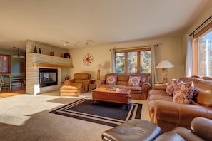 A cozy living room with a fireplace, leather sofas, a coffee table, and a large window. - 72 Clubhouse Rd Private Home with Hot Tub (Breckenridge)