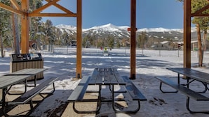 A covered picnic area with benches and a trash bin, overlooking a snowy mountain landscape. - Atrium 104 Downtown Condos with on-site Hot Tub (Breckenridge)