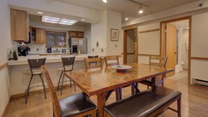 A spacious kitchen with wooden cabinets, a dining table with chairs, and a refrigerator. - Atrium 104 Downtown Condos with on-site Hot Tub (Breckenridge)