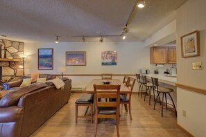 A dining area with a wooden table and chairs, a brown leather sofa, and framed artwork on the walls.