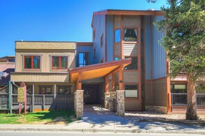 A modern multi-story building with a covered entrance and stone pillars.
