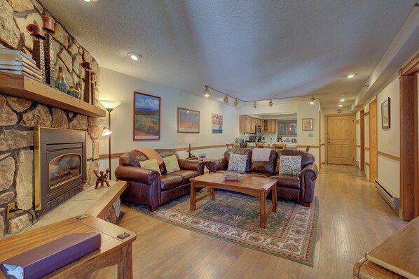 A spacious living room with a stone fireplace, leather sofas, and a wooden coffee table.
