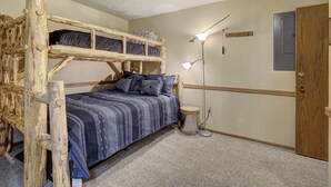 A bunk bed with a blue patterned bedspread, a bedside lamp, and a wooden door. - Atrium 104 Downtown Condos with on-site Hot Tub (Breckenridge)