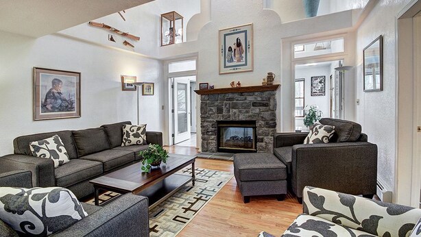 A spacious living room with a stone fireplace, two sofas, a coffee table, and a large rug. - Casa De Alta Peak 9  Private Home with Hot Tub (Breckenridge)