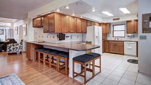 A modern kitchen with wooden cabinets, a central island with bar stools, and a refrigerator. - Casa De Alta Peak 9  Private Home with Hot Tub (Breckenridge)