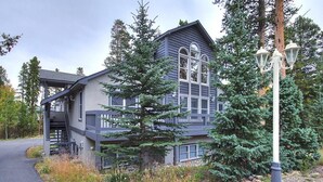 A two-story house with a covered porch, a large window, and a staircase leading to the upper level. - Casa De Alta Peak 9  Private Home with Hot Tub (Breckenridge)