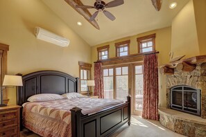 Ein Schlafzimmer mit Bett, Deckenventilator, Kamin und großen Fenstern.