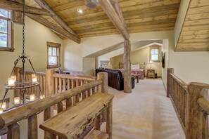 Ein rustikaler Innenraum mit einer Holztreppe, einer Essecke mit einer Bank und einem Schlafzimmer mit Bett und Kommode.