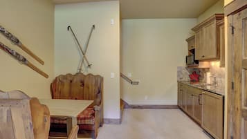 A kitchen with wooden cabinets, a dining table, and a staircase leading to another level.