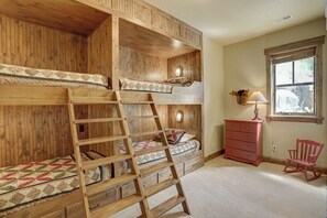 Quarto com beliche, cômoda, abajur e cadeira de balanço.