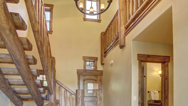 Una scala in legno con corrimano, che porta a un pianerottolo con una porta e una finestra.