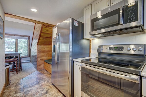 A modern kitchen with stainless steel appliances, including a refrigerator, microwave, and oven.