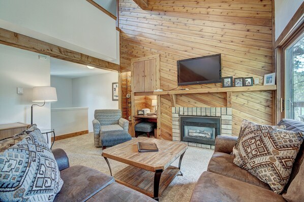 A cozy living room with a fireplace, wooden walls, a flat-screen TV, and comfortable seating. - Lance's West 6 Condo with Pool & Hot Tub (Breckenridge)