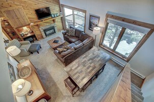 A spacious living area with a fireplace, a large window, and a television mounted on the wall.